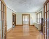 Unfurnished room featuring radiator heating unit, light hardwood / wood-style flooring, french doors, and ornamental molding