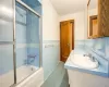 Bathroom with vanity, tile patterned floors, tile walls, and bath / shower combo with glass door