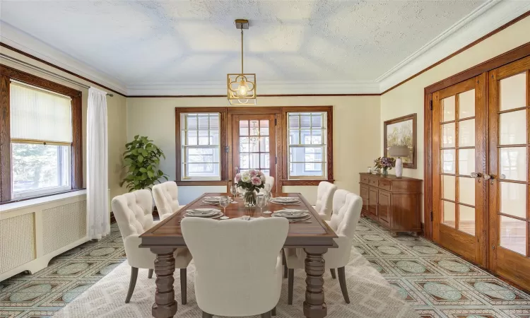 Staged - Dining area with french doors, a textured ceiling, and crown molding