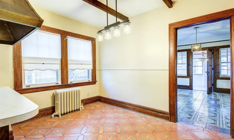 Unfurnished dining area featuring beamed ceiling, radiator heating unit, and tile patterned floors