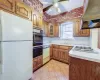 Kitchen with ceiling fan, sink, brick wall, white appliances, and custom range hood