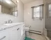 1st Fl - Full Bathroom featuring tile walls, toilet, shower, tile floors, vanity, and baseboard heat