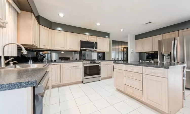 Kitchen w/stainless steel appliances, light tile floors, tasteful backsplash, a kitchen island