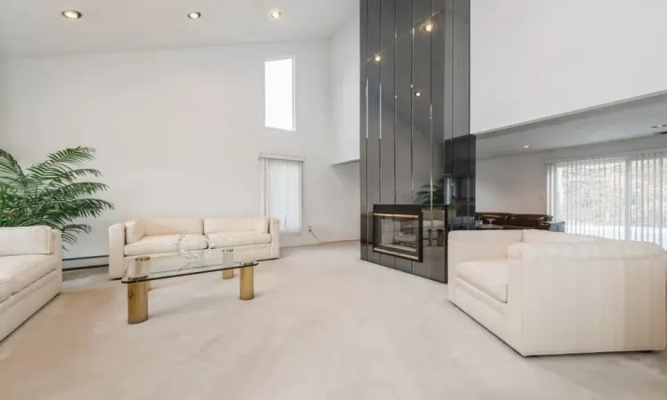 Gas Fireplace in Formal Living room featuring a towering ceiling& baseboard heating