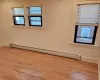 Unfurnished room with a baseboard heating unit and light wood-type flooring