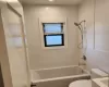 Full bathroom featuring toilet, tiled shower / bath, tile walls, and vanity