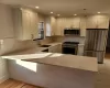 Kitchen with kitchen peninsula, light hardwood / wood-style flooring, white cabinets, appliances with stainless steel finishes, and sink