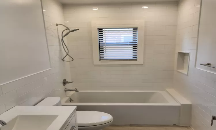 Full bathroom with toilet, vanity, tile walls, and tiled shower / bath