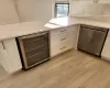 Kitchen with beverage cooler, dishwasher, and white cabinetry