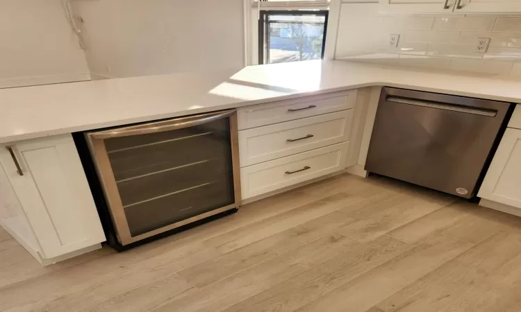 Kitchen with beverage cooler, dishwasher, and white cabinetry