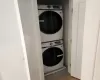 Clothes washing area with stacked washer / drying machine and hardwood / wood-style flooring