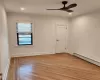 Empty room featuring a baseboard radiator, ceiling fan, and light hardwood / wood-style floors