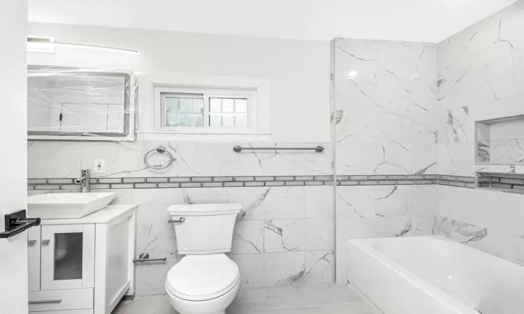 Bathroom with toilet, tile walls, and vanity