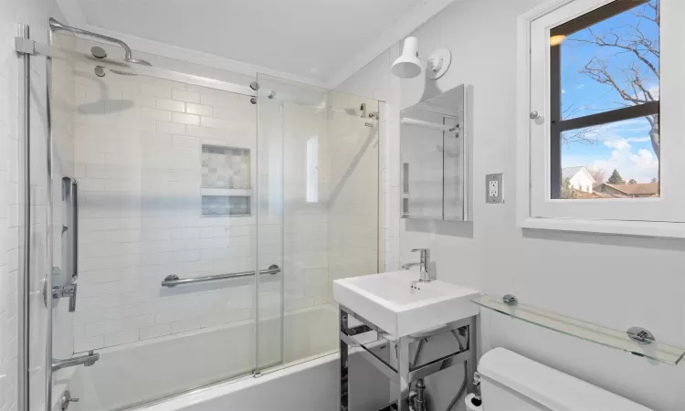 Bathroom featuring shower / bath combination with glass door, toilet, and ornamental molding