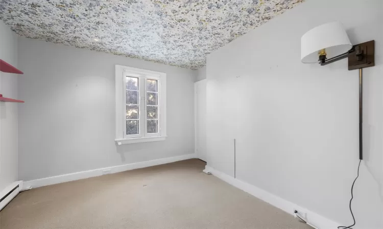 Carpeted empty room featuring a baseboard radiator