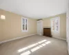 Unfurnished room featuring a healthy amount of sunlight, light colored carpet, and radiator heating unit