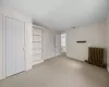 Unfurnished bedroom featuring a closet, radiator heating unit, and carpet floors