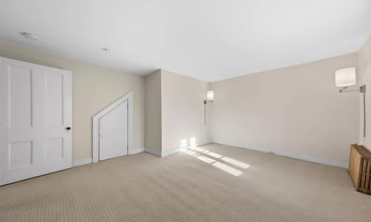 Carpeted empty room featuring radiator