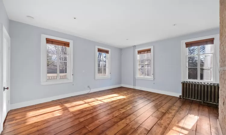 Spare room featuring radiator and wood-type flooring