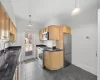 Kitchen with light brown cabinets, dark stone counters, sink, hanging light fixtures, and stainless steel appliances