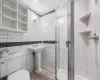 Bathroom with walk in shower, wood-type flooring, toilet, and tile walls