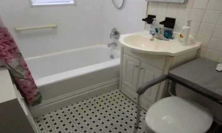 Full bathroom featuring tile patterned flooring, tile walls, toilet, shower / bath combo, and vanity