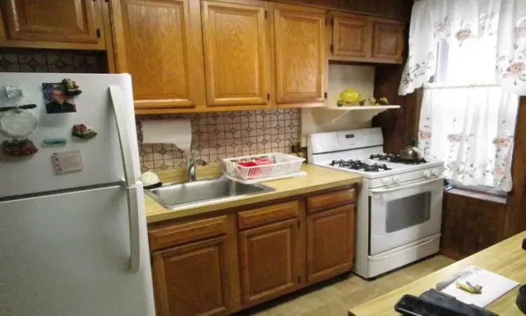 Kitchen with white appliances, decorative backsplash, and sink