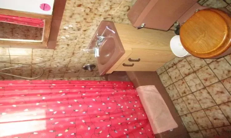 Full bathroom featuring sink, tile patterned floors, toilet, and shower / bath combo with shower curtain