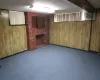 Basement featuring a brick fireplace, an AC wall unit, wooden walls, and carpet