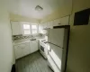 Kitchen with white appliances, electric panel, decorative backsplash, white cabinetry, and sink