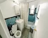 Full bathroom with tile walls, toilet, vanity, and shower / bathtub combination with curtain