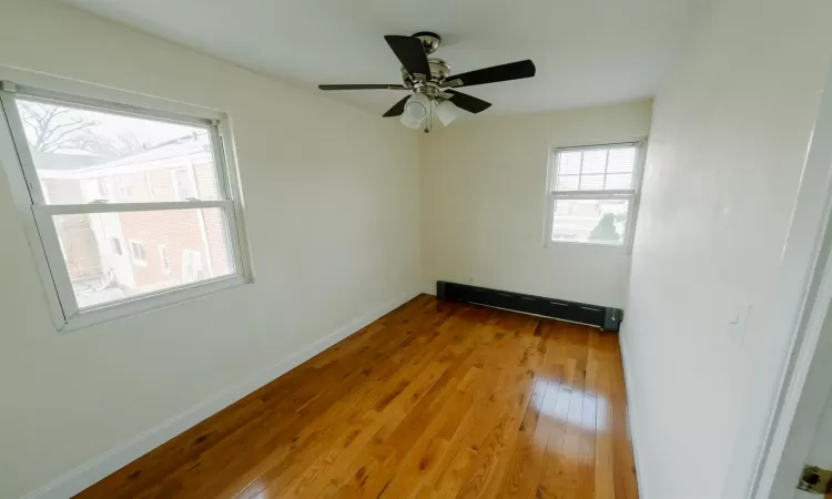 Unfurnished room with a baseboard radiator, light wood-type flooring, and ceiling fan