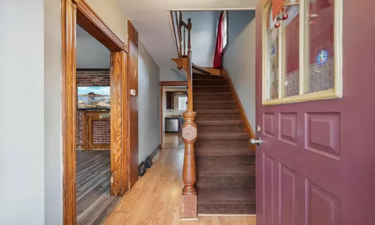 Foyer with light wood-type flooring and brick wall