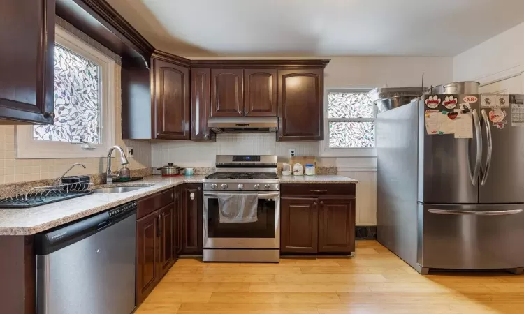 Kitchen featuring stainless steel appliances, sink, light hardwood / wood-style floors, and dark brown cabinetry