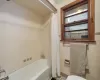 Bathroom featuring tile walls, shower / bath combination with curtain, and toilet