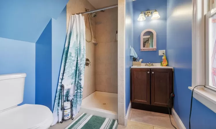 Bathroom with tile patterned flooring, toilet, a shower with shower curtain, vanity, and lofted ceiling