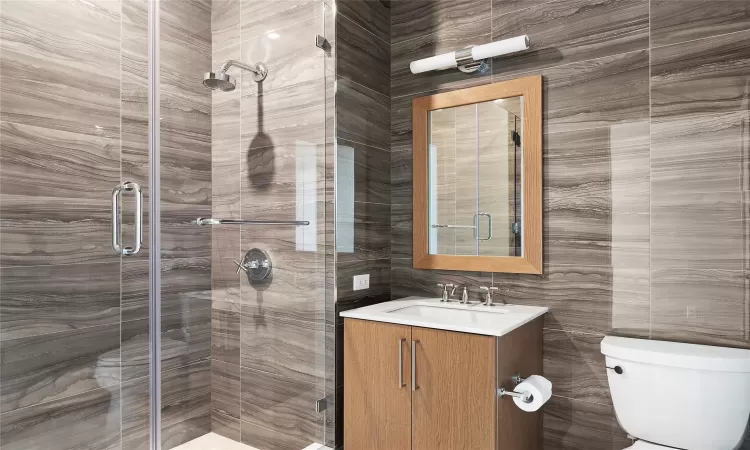 Bathroom featuring vanity, toilet, and a shower with door