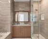 Bathroom featuring vanity, walk in shower, and tile walls