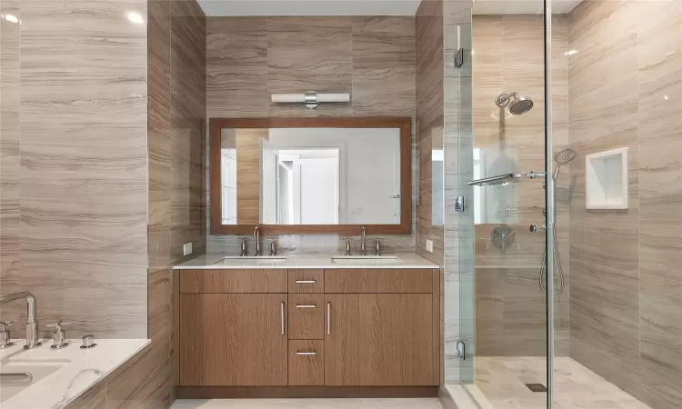 Bathroom featuring vanity, walk in shower, and tile walls