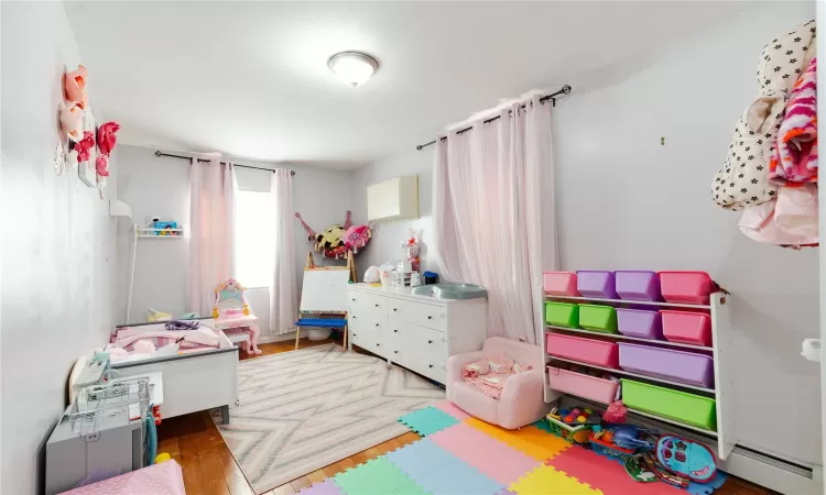 Playroom with a baseboard heating unit and hardwood / wood-style flooring