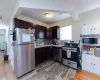 Kitchen with light wood-type flooring, appliances with stainless steel finishes, backsplash, and sink