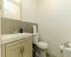 Bathroom with radiator, vanity, toilet, and tile walls