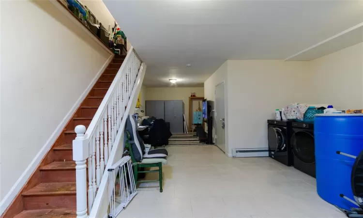 Basement with baseboard heating and washing machine and clothes dryer