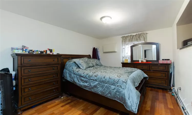 Bedroom with dark wood-type flooring and a baseboard radiator