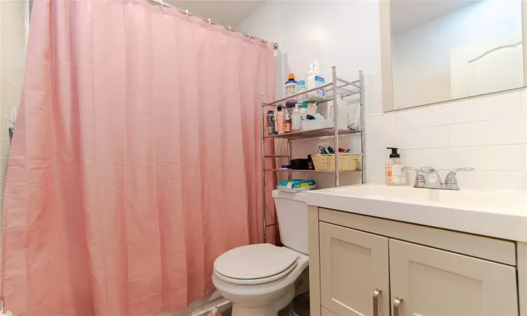 Bathroom featuring toilet, vanity, tasteful backsplash, and curtained shower