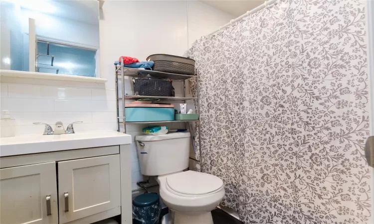 Bathroom featuring toilet, tasteful backsplash, and vanity