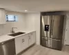 Kitchen with appliances with stainless steel finishes, light wood-type flooring, sink, white cabinets, and tasteful backsplash