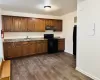 Kitchen featuring dark wood-type flooring, dark stone counters, black appliances, and sink