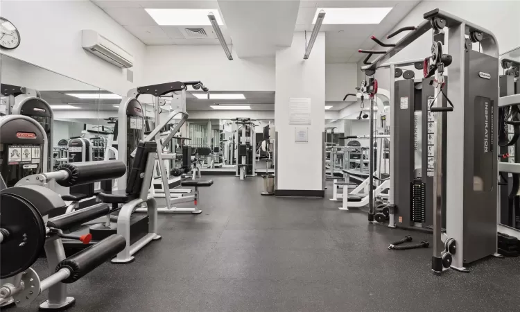 Exercise room with a paneled ceiling and an AC wall unit