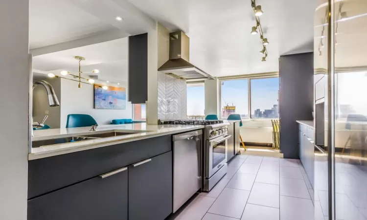 Kitchen with island exhaust hood, stainless steel appliances, pendant lighting, sink, and tasteful backsplash